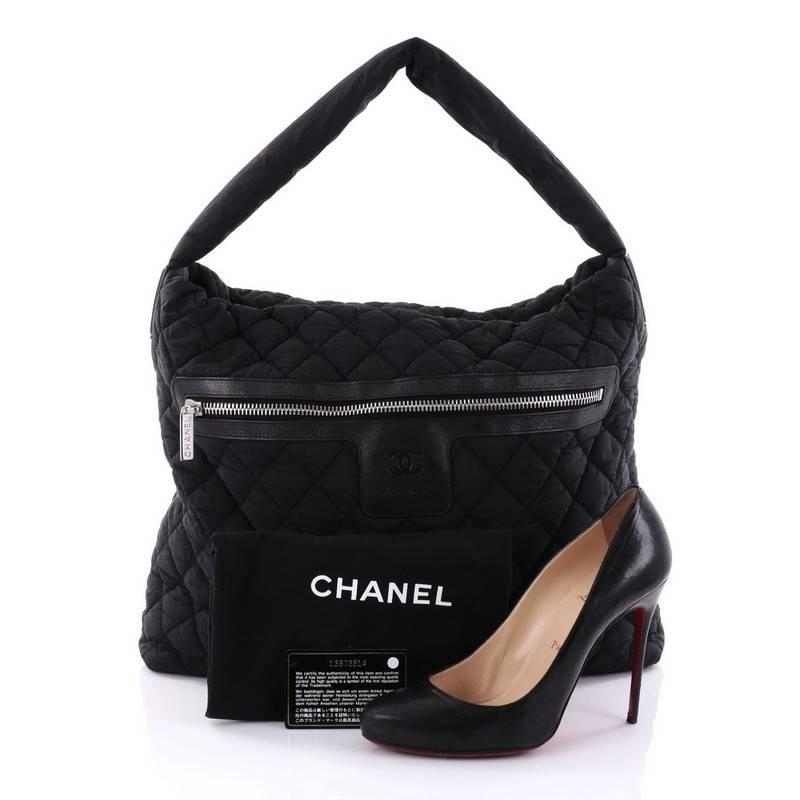 This authentic Chanel Coco Cocoon Hobo Quilted Nylon Medium is a highly sought after piece from Lagerfeld's fun and chic Coco Cocoon line. Crafted from black quilted nylon, this sporty-chic hobo features padded top handle, interlocking CC logo