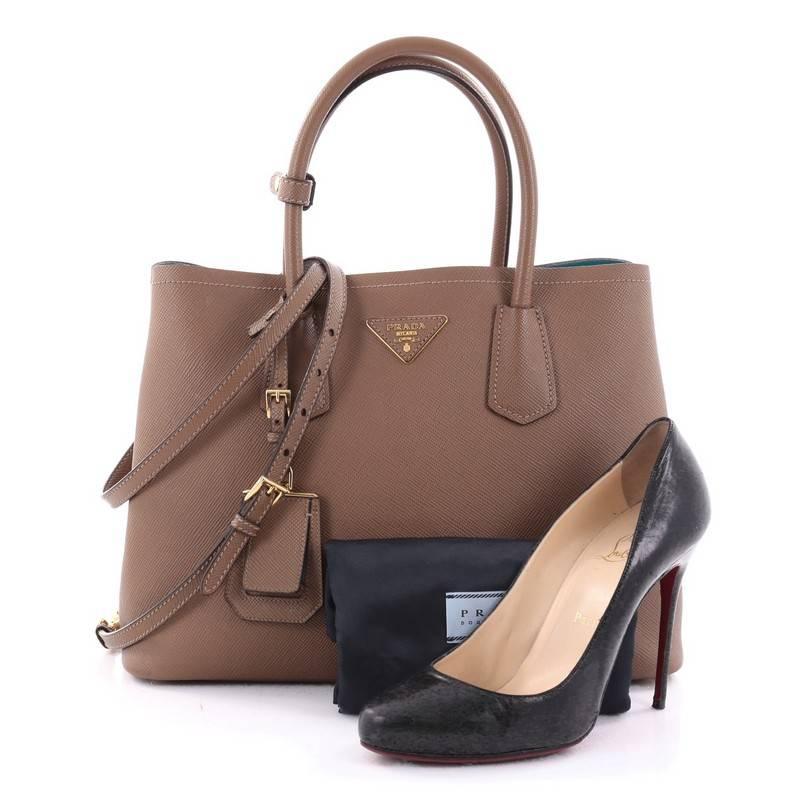 This authentic Prada Cuir Double Tote Saffiano Leather Small updates its popular Cuir line with a fresh, twist. Crafted from light brown saffiano leather, this luxurious tote features dual-rolled top handles, side snap buttons, Prada's trademark