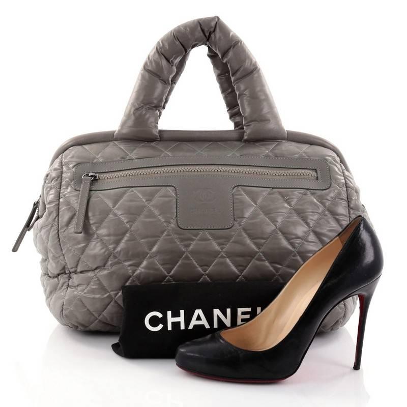 This authentic Chanel Coco Cocoon Bowling Bag Quilted Nylon is a highly sought after piece from Lagerfeld's fun and chic Coco Cocoon line. Crafted from puffy greyish-green quilted nylon, this lightweight, stylish bowler bag features dual-rolled