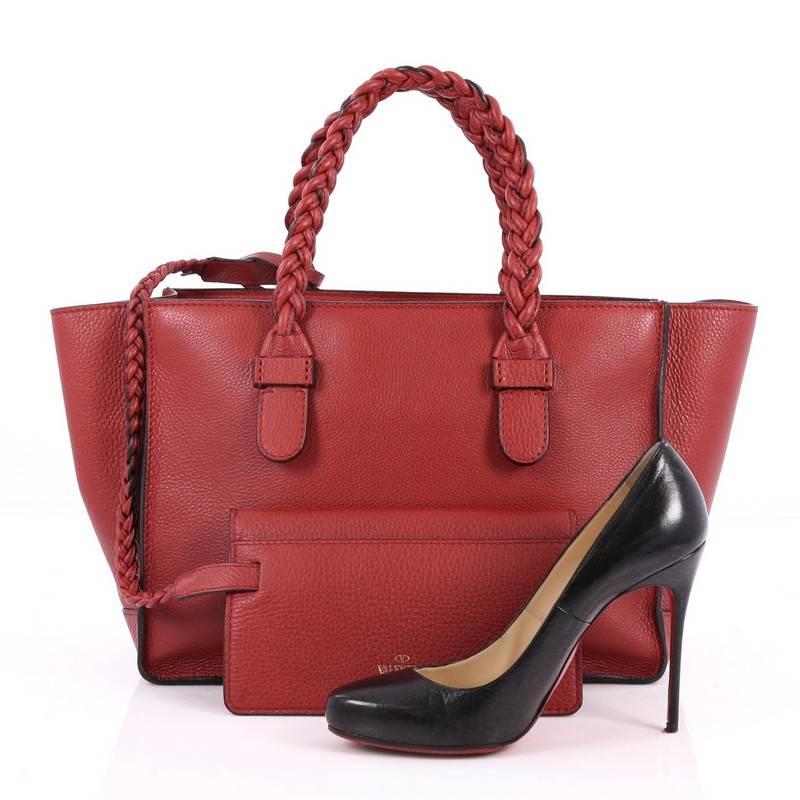 This authentic Valentino To Be Cool Tote Leather Small is a stylish and iconic tote made for everyday excursions. Crafted from red grainy leather, this feminine tote features dual braided top handles, gold-stamped logo at front, and gold-tone