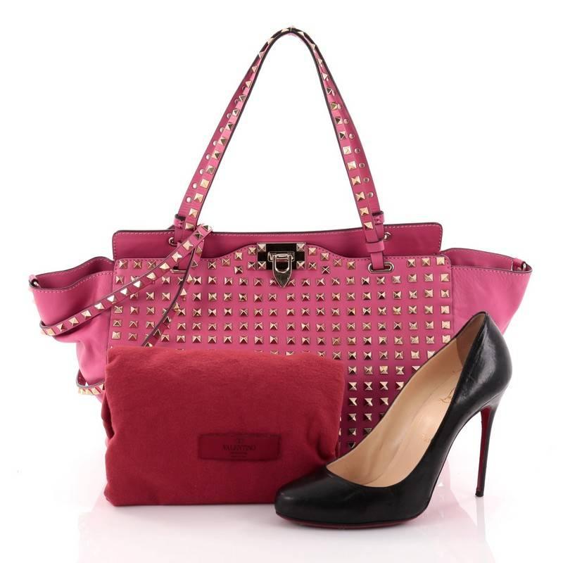 This authentic Valentino Rockstud Tote Full Studded Leather Medium mixes edgy style with luxurious detailing. Crafted from pink studded leather, this stylish tote features dual tall flat handles, gold-tone pyramid studs, a signature clasp fastening,