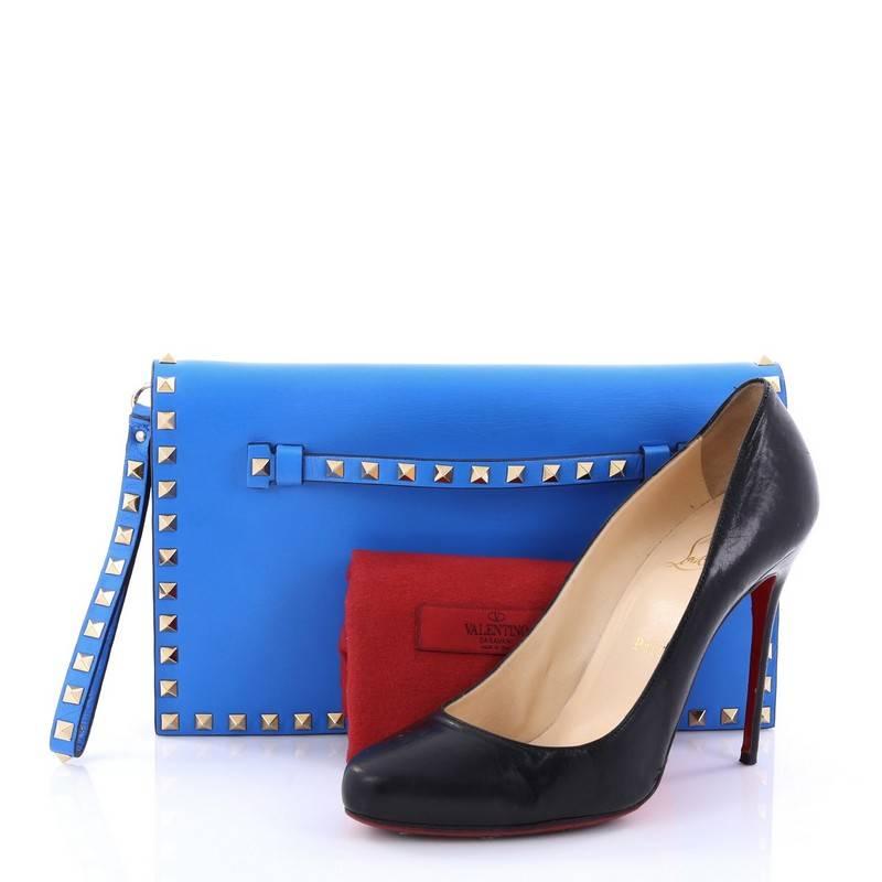 This authentic Valentino Rockstud Flap Clutch Leather is a chic yet functional accessory perfect for on-the-go moments. Crafted from blue leather, this trendy clutch features a detachable leather hand sling, gold studded hand strap, polished gold