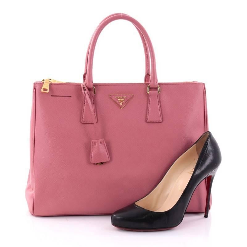 This authentic Prada Double Zip Lux Tote Saffiano Leather Medium is the perfect bag to complete any outfit. Crafted from pink saffiano leather, this boxy tote features side snap buttons, raised Prada logo, dual-rolled leather handles and gold-tone