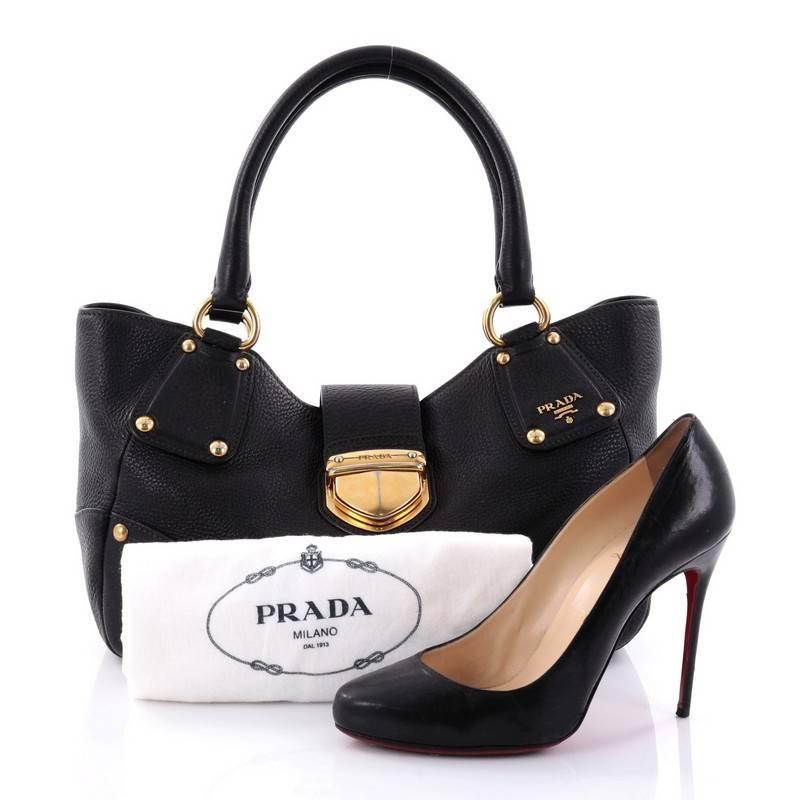 This authentic Prada Pushlock Tote Vitello Daino Medium is the ideal bag for everyday use and light traveling. Constructed from nero black vitello daino leather, this simple tote features dual-rolled leather handles, protective base studs, and
