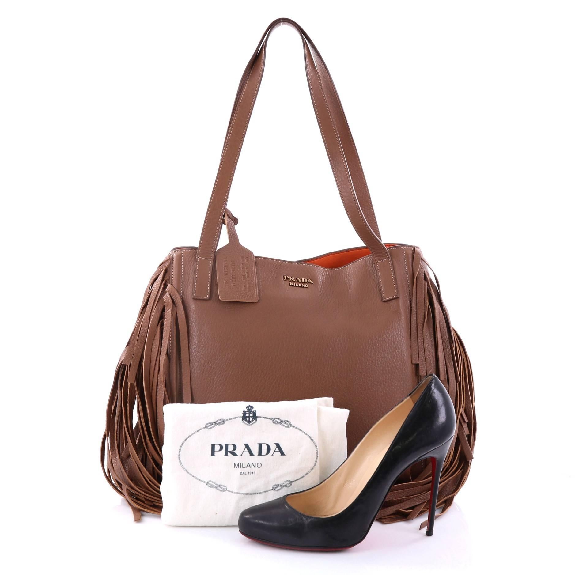 This authentic Prada Fringe Tote Cervo Leather Large combines classic and easy style with a chic twist perfect for daily excursions. Crafted from brown cervo leather, this 70s-inspired stylish tote features cascading fringe details at its sides,
