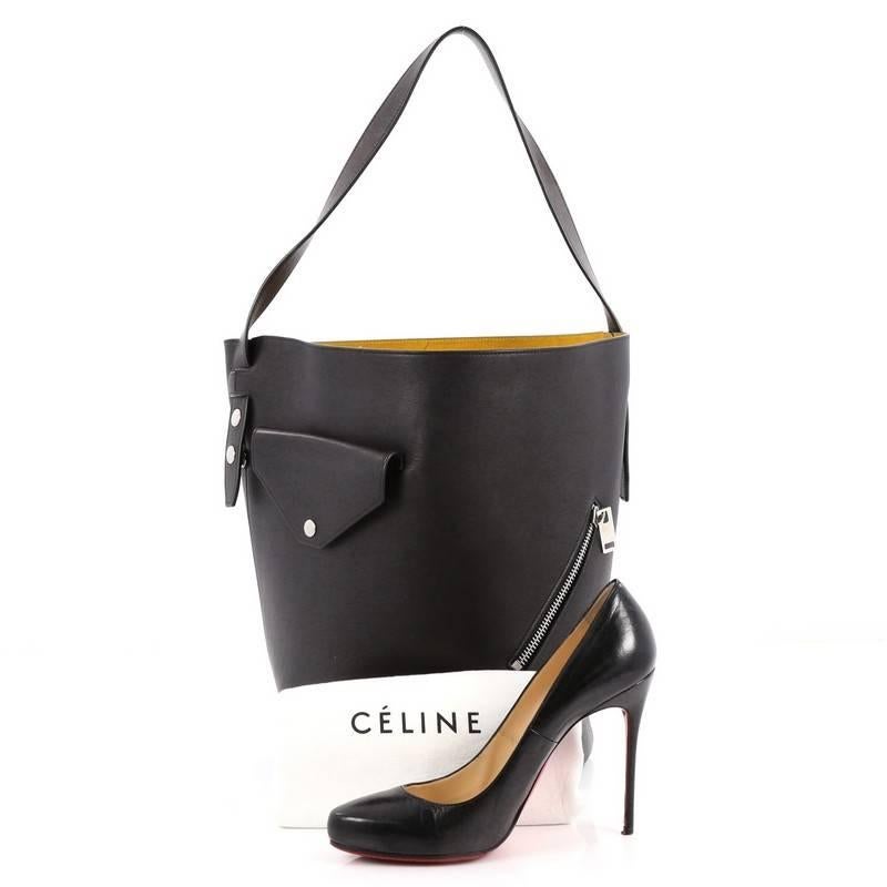 This authentic Celine Biker Bucket Shoulder Bag Calfskin Small is an excellent bag for everyday use. Crafted in black leather, this edgy bag features tall leather strap handle, exterior zipper and patch pockets, stud detailing and silver-tone