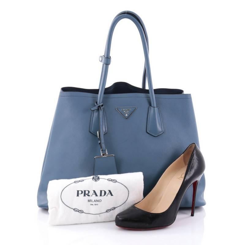 This authentic Prada Cuir Double Tote City Calfskin Medium is a mark of Prada's fine craftsmanship that is elegant in its simplicity and structure. Crafted from blue city calfskin leather, this tote features dual-rolled handles, side snap buttons,