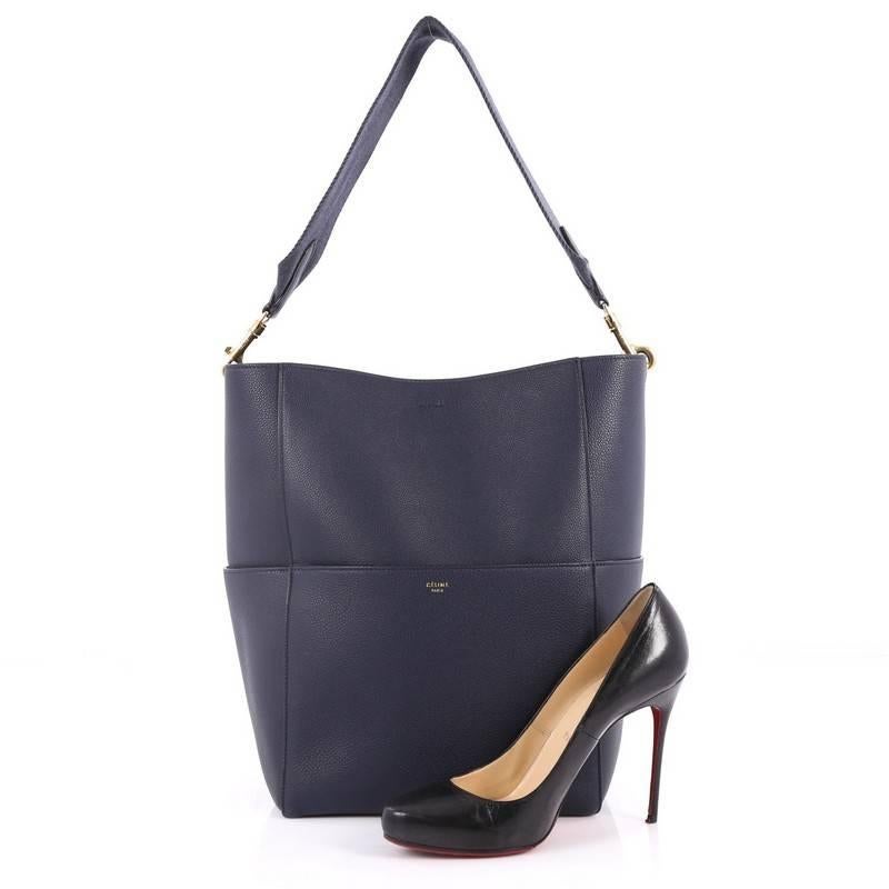 This authentic Celine Sangle Seau Handbag Goatskin Large balances a simple yet luxurious style perfect for an on-the-go woman. Crafted from navy blue goatskin leather, this minimalist bucket bag features a detachable canvas shoulder strap, multiple