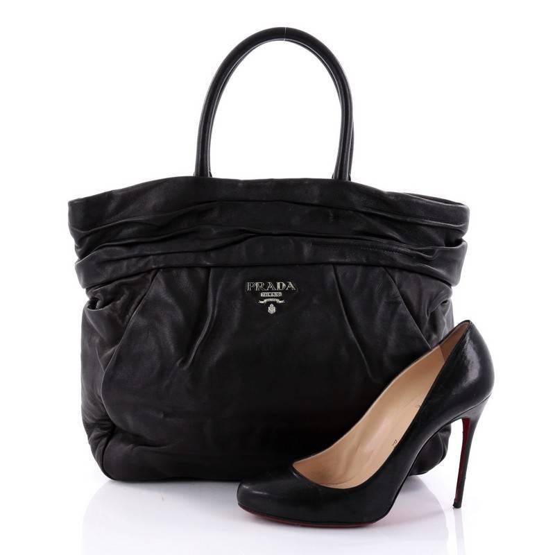 This authentic Prada Frills Tote Nappa Leather Medium balances a traditional design with a chic and sleek twist perfect for modern fashionistas. Crafted in nero black nappa leather, this stylish tote features pleated leather detailing, dual-rolled