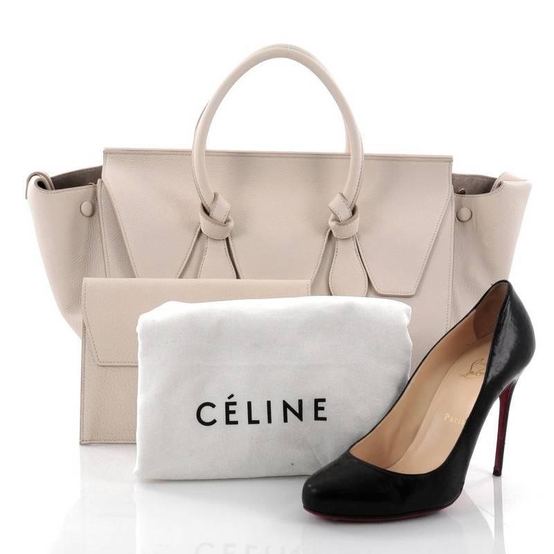 This authentic Celine Tie Knot Tote Grainy Leather Medium is an absolute must-have for serious fashionistas. Crafted from beige grainy leather, this boxy chic tote features dual-rolled leather handles with signature knot accents, expandable wings