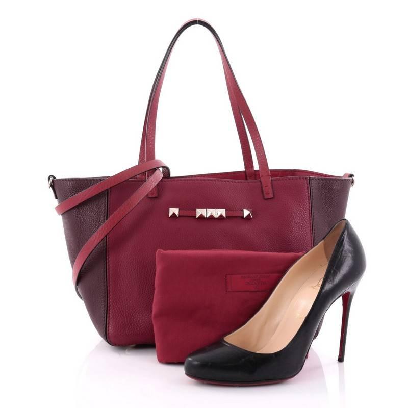 This authentic Valentino Rockstud Convertible Open Tote Leather Small is the perfect everyday bag for an on-the-go fashionista. Crafted in red leather with burgundy wings, this tote features dual flat leather handles, detachable strap, brand's