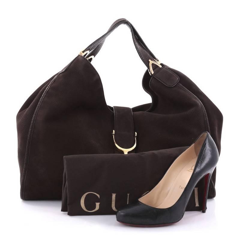 This authentic Gucci Soft Stirrup Tote Nubuck Large in luxurious and sleek design is made for all seasons. Crafted in brown nubuck, this hobo-style shoulder bag features side to side looped dual-flat handles with unique spur detailing and gold-tone