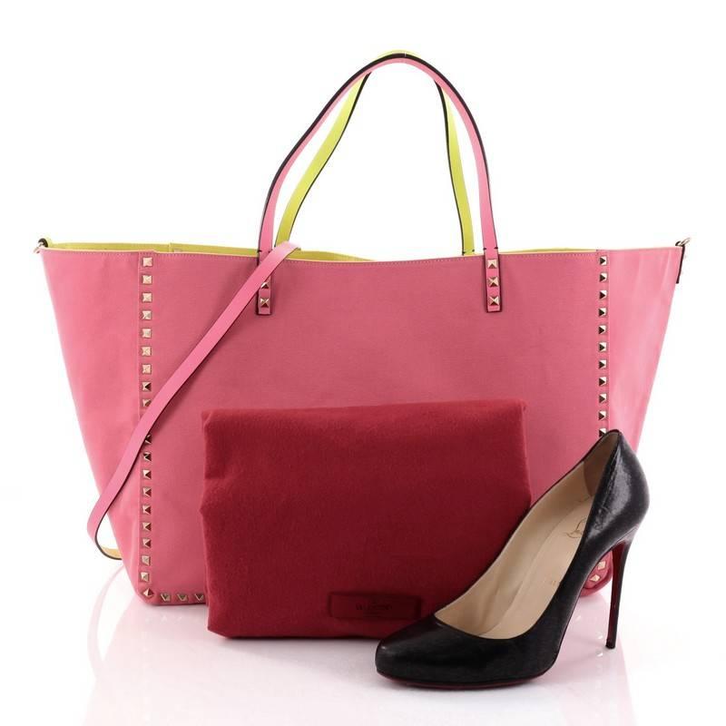 This authentic Valentino Rockstud Reversible Convertible Tote Leather Large is the perfect daily bag for an on-the-go fashionista. Crafted from pink and yellow reversible leather, this tote features the brand's iconic pyramid rockstud detailing,