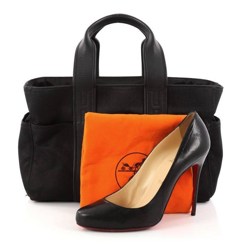 This authentic, Hermes Acapulco Tote Toile and Leather PM showcases a simple yet chic tote perfect for daily excursions and light traveling. Crafted in black toile and leather, this travel tote features dual flat leather handles, exterior slip