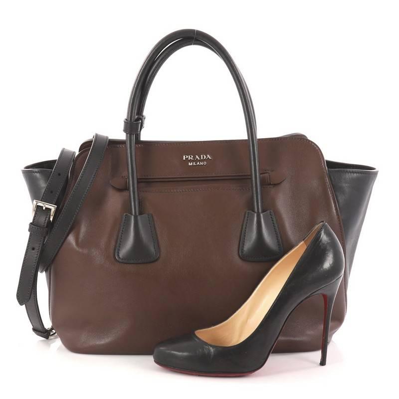 This authentic Prada Cuir Convertible Shopping Tote Soft Calfskin Large is elegant in its simplicity and structure. Crafted in brown and black soft calfskin leather, this tote features dual-rolled handles, expandable side wings, protective base