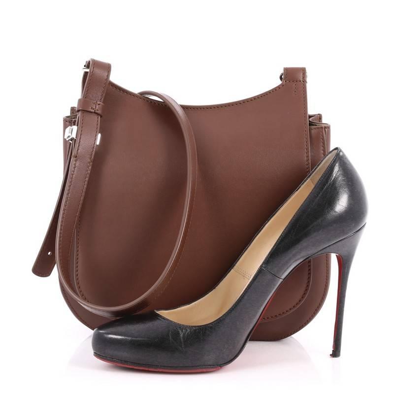 This authentic The Row Hunting Crossbody Bag Leather 9 is a sleek and minimalist bag ideal for everyday use. Crafted in brown leather, this saddle-style crossbody bag features an adjustable leather strap, back slip pocket and silver-tone hardware