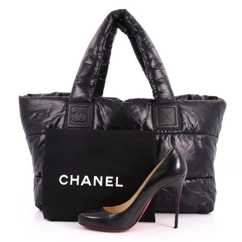 This authentic Chanel Coco Cocoon Reversible Tote Quilted Nylon Medium is a highly sought-after piece from Lagerfeld's fun and chic Coco Cocoon line. Crafted from black quilted nylon, this sporty tote features padded top handles, interlocking CC