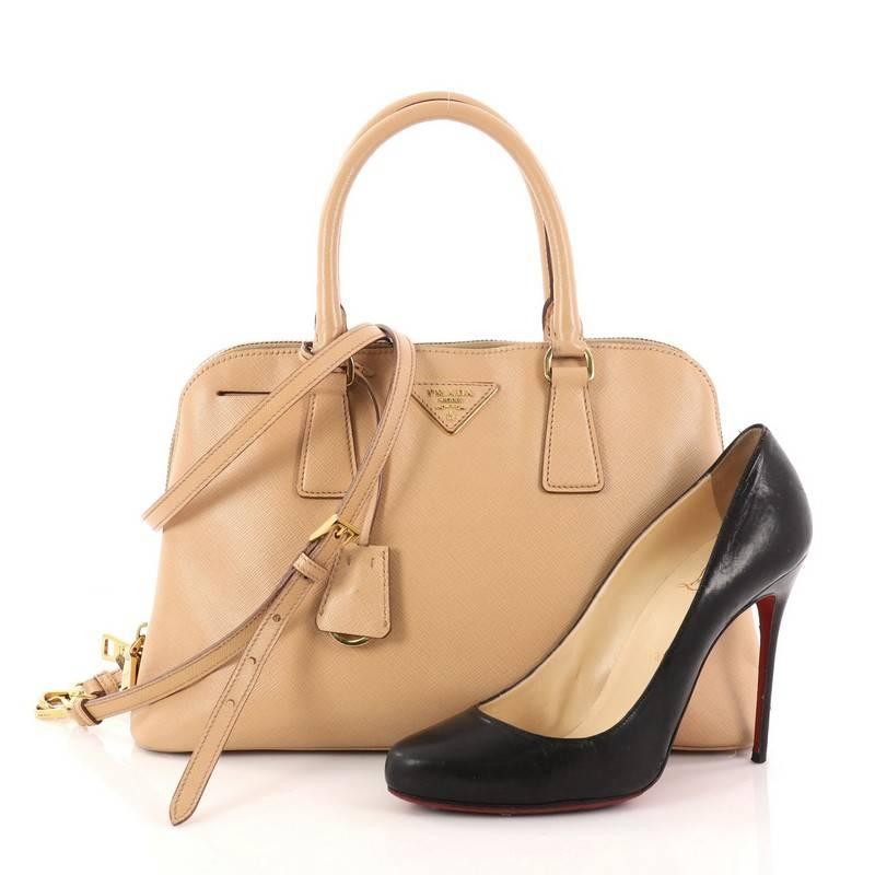 This authentic Prada Promenade Handbag Saffiano Leather Medium is elegant in its simplicity and structure. Crafted in nude saffiano leather, this sleek dome-shaped satchel features dual-rolled handles, protective base studs, Prada logo at the center