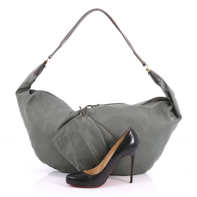 This authentic The Row Sling Hobo Nylon 15 is a versatile and travel-friendly bag. Crafted in green nylon, this chic bag features wide flat leather strap and gold-tone hardware accents. Its zip closure opens to a green nylon-lined interior with slip