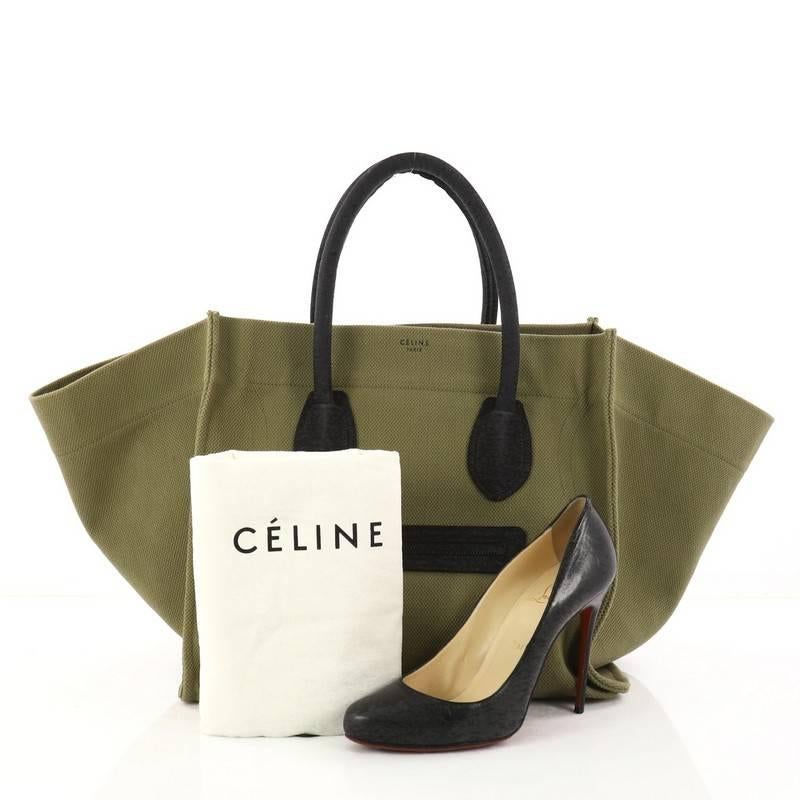 This authentic Celine Phantom Handbag Canvas Large is one of the most sought-after bags beloved by many fashionistas. Crafted from green canvas, this minimalist tote features dual-rolled handles, an exterior front pocket, protective base studs,