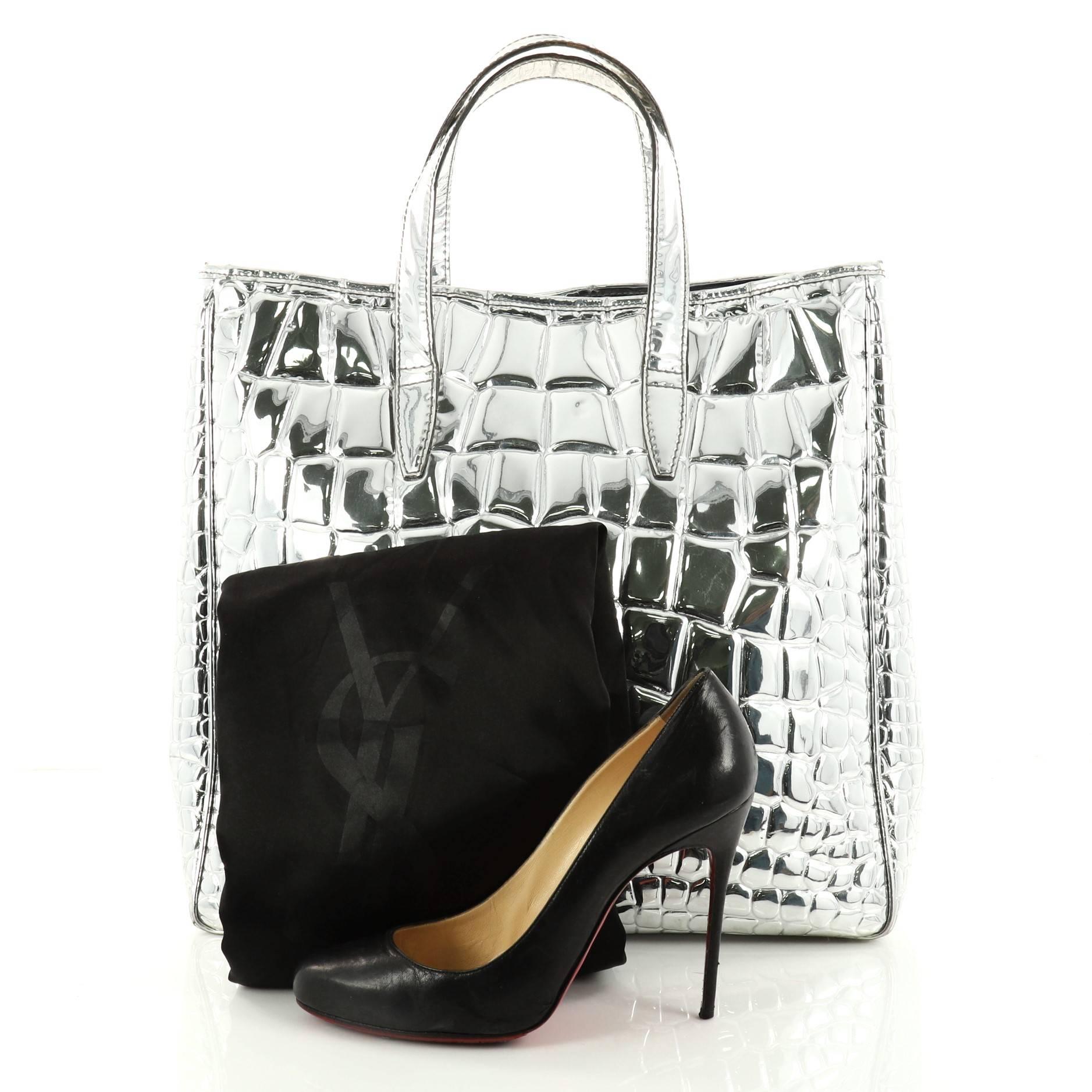 This authentic Saint Laurent Raspail Tote Crocodile Embossed Mirror Leather Medium is a stylish and gorgeous bag that will add an edge to any outfit. Crafted in silver crocodile embossed mirror leather, this tote features dual flat leather handles,