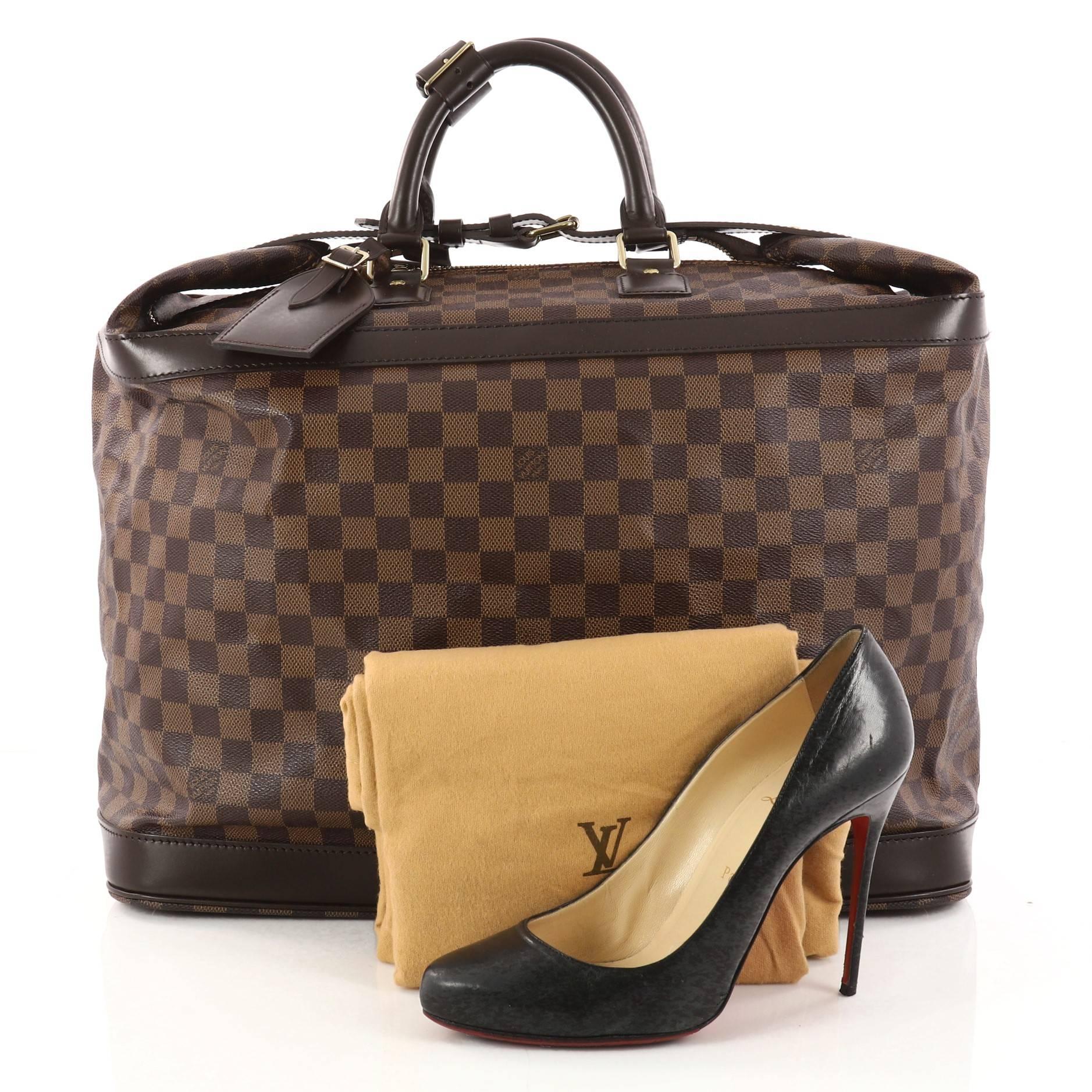 This authentic Louis Vuitton Cruiser Handbag Damier 45 showcases the brand's timeless and luxurious style and functionality. Crafted in Louis Vuitton's iconic damier ebene coated canvas, this chic travel luggage features dual-rolled handles, dark