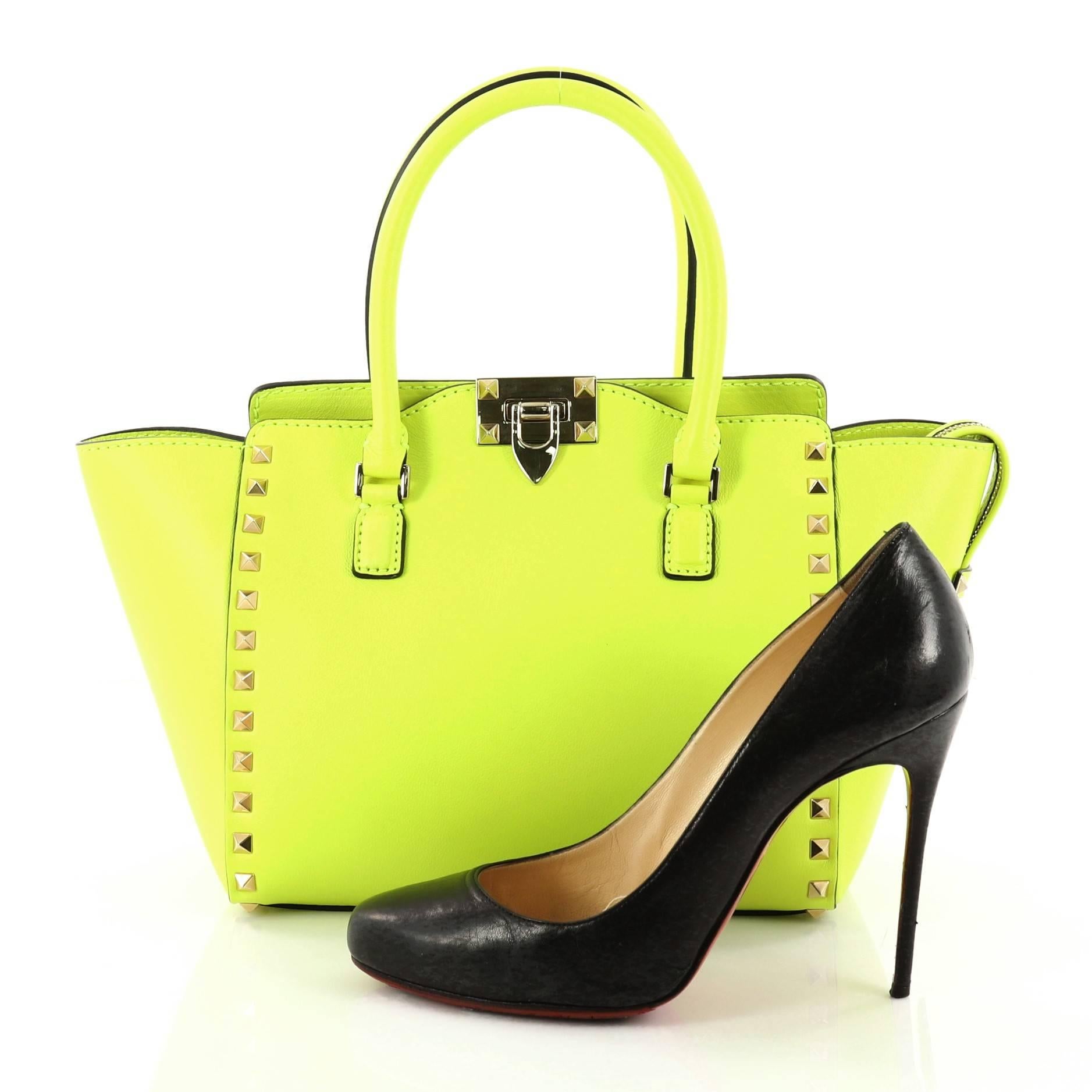 This authentic Valentino Rockstud Tote Rigid Leather Small is the perfect daily bag for the on-the-go fashionista. Crafted in sleek neon green rigid leather, this stylishly structured tote features tall dual-rolled handles, gold-tone pyramid stud