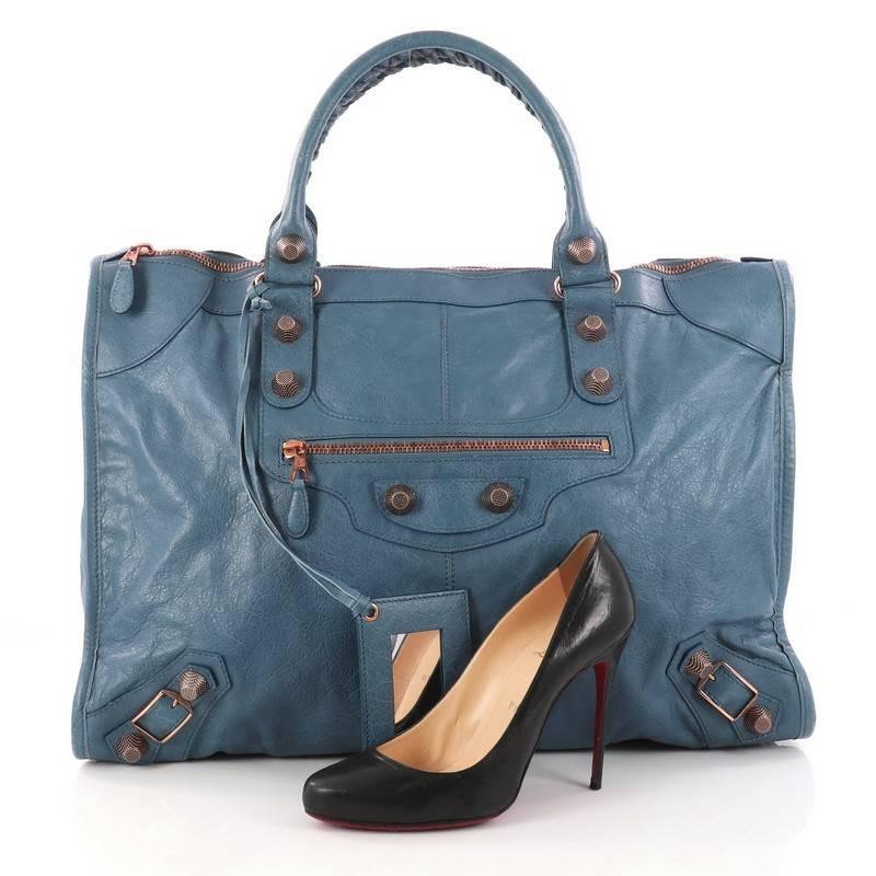 This authentic Balenciaga Weekender Giant Studs Handbag Leather is a stylish and fun duffle made for light travels and weekend getaways. Constructed from blue leather, this lightweight bag features braided woven handles, front zipped pocket, and