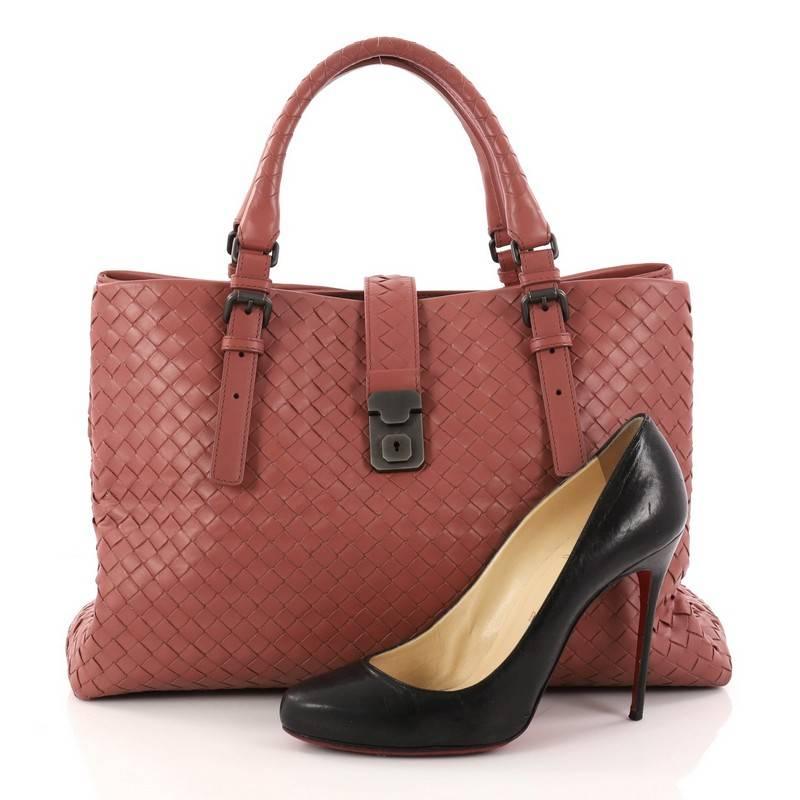 This authentic Bottega Veneta Roma Handbag Intrecciato Nappa Medium is a finely crafted tote that exudes an understated elegance. Crafted from pink nappa leather woven in Bottega Veneta's signature intrecciato method, it features dual woven leather