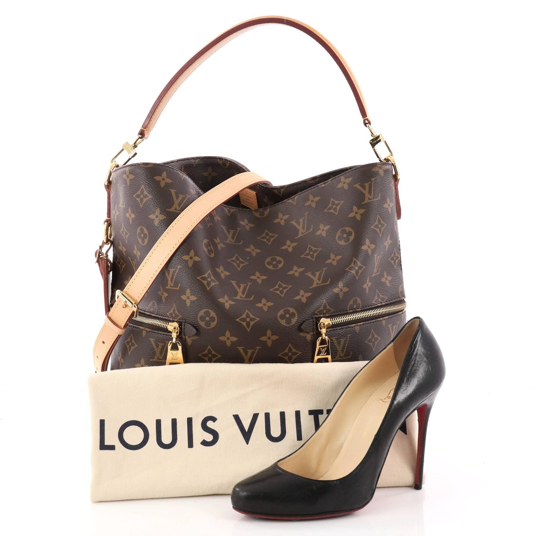 This authentic Louis Vuitton Melie Handbag Monogram Canvas is a fresh take on the classic hobo design. Crafted in brown monogram coated canvas, this bag features a flat leather short handle, two exterior zip pockets, protective base studs and
