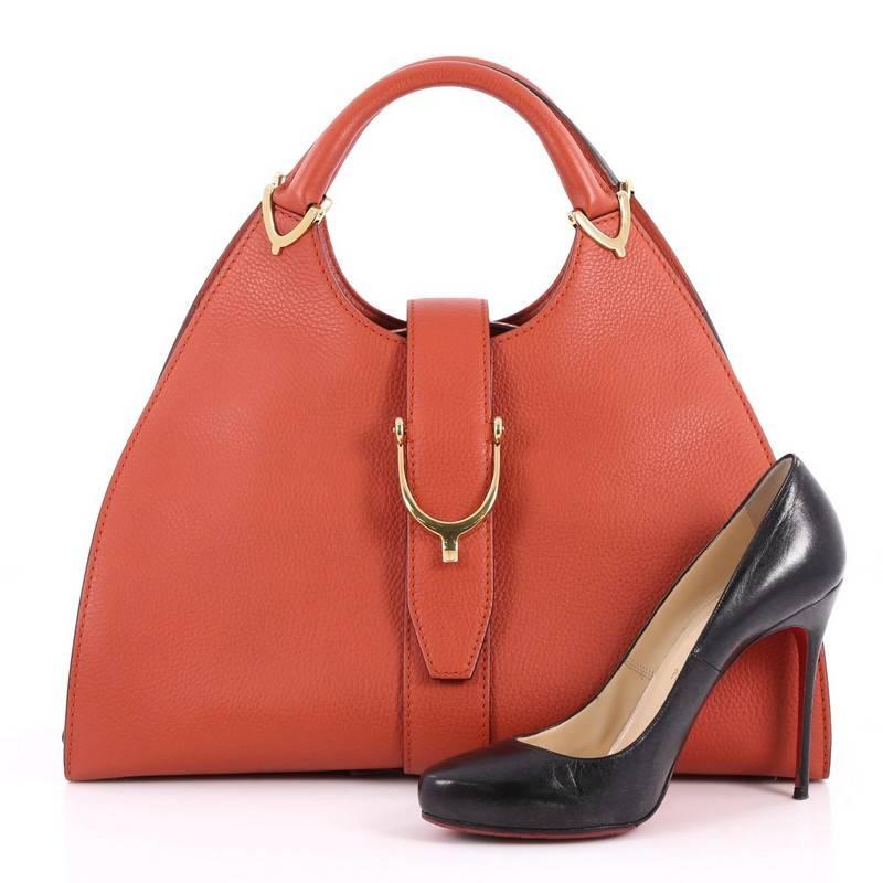 This authentic Gucci Stirrup Top Handle Bag Leather Large inspired by its 1975 iconic design is an elegant bag with trademark equestrian flair. Crafted from burnt orange leather, this structured bag features dual-rolled handles with spur details,