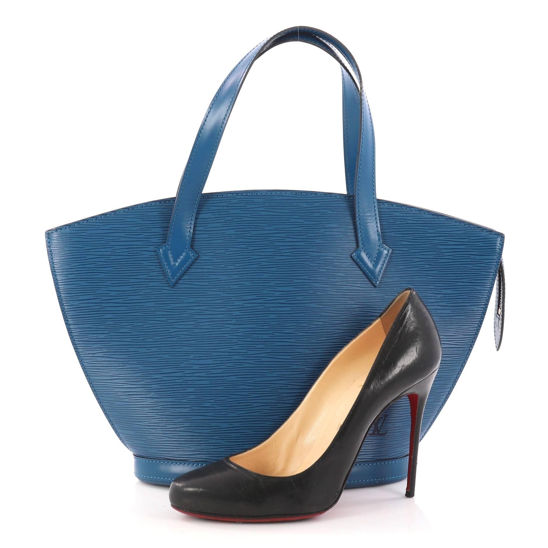 This authentic Louis Vuitton Saint Jacques Handbag Epi Leather PM is refined and elegant. Crafted from Louis Vuitton's signature blue epi leather and sturdy base, this fan-shaped bag features dual-flatleather straps, subtle LV logo at the front and
