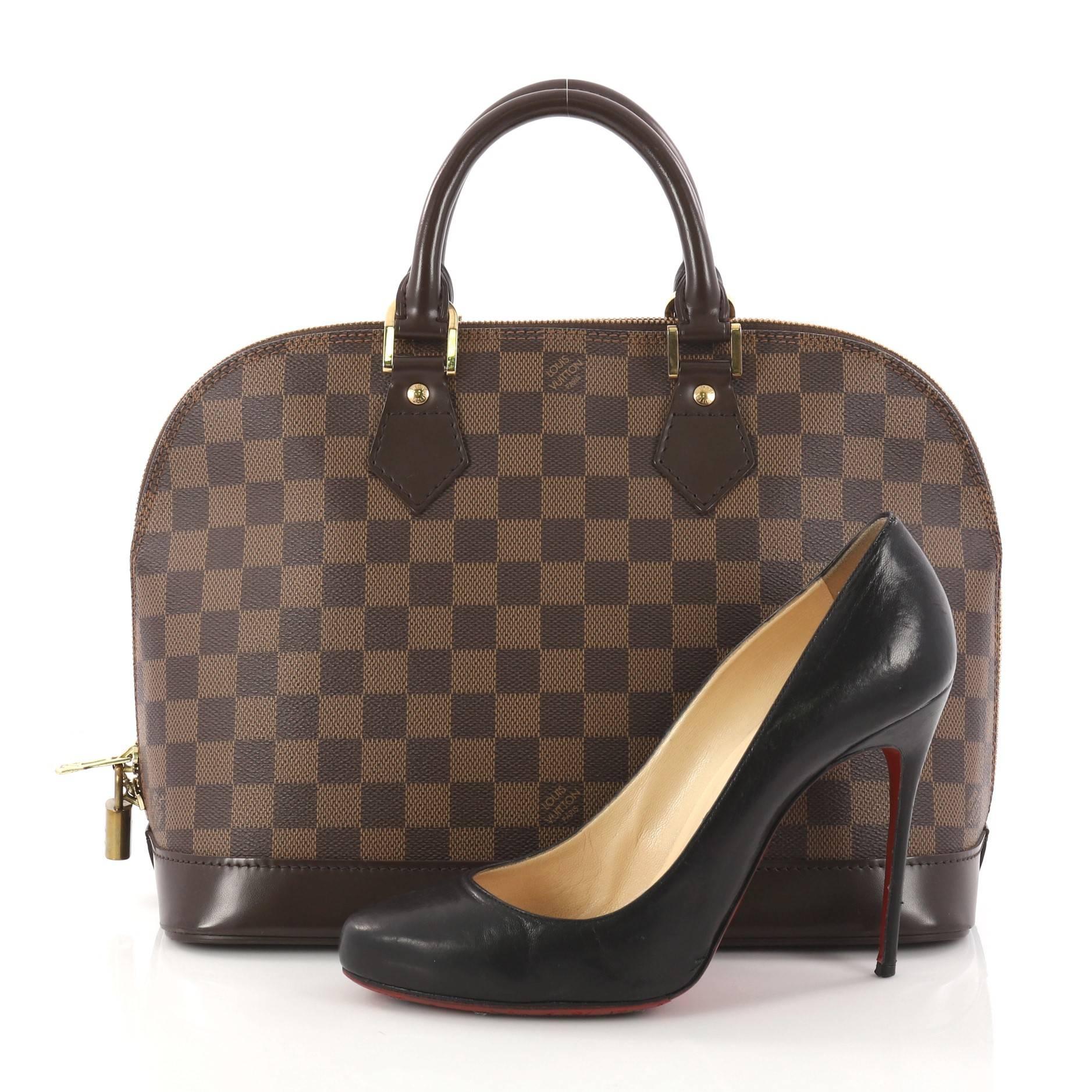 This authentic Louis Vuitton Vintage Alma Handbag Damier PM is an elegant spin on a classic style that is perfect for all seasons. Crafted from Louis Vuitton's damier ebene coated canvas, this iconic dome-shaped satchel features dual-rolled handles,