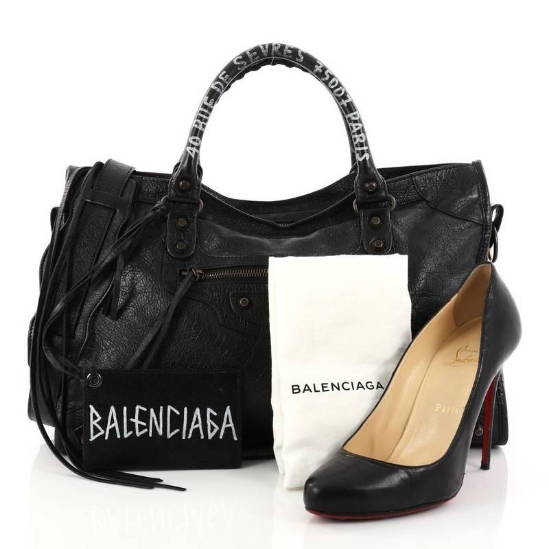 This authentic Balenciaga City Address Graffiti Classic Studs Handbag Leather Medium is for the on-the-go fashionista. Constructed in black leather, this popular bag features dual braided woven handles with graffiti address, front zip pocket, iconic
