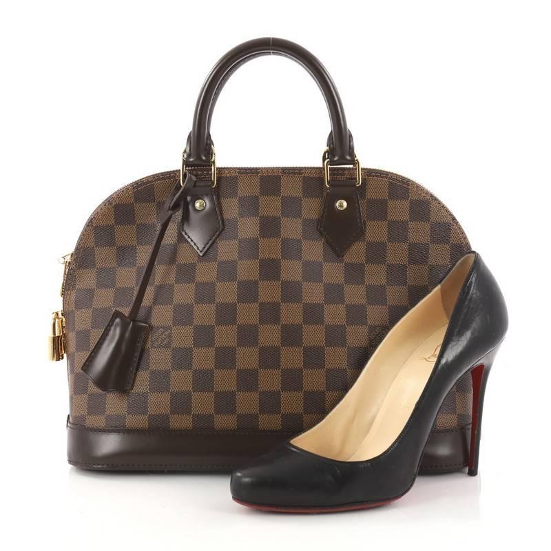 This authentic Louis Vuitton Alma Handbag Damier PM is an elegant spin on a classic style perfect for all seasons. Crafted from Louis Vuitton's damier ebene coated canvas, this dome-shaped satchel features dual-rolled handles, dark brown leather