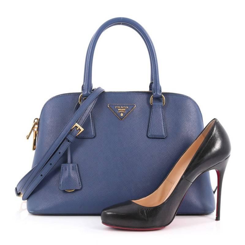 This authentic Prada Promenade Handbag Saffiano Leather Medium is elegant in its simplicity and structure. Crafted in blue saffiano leather, this sleek dome-shaped satchel features dual-rolled handles, protective base studs, Prada logo at the center