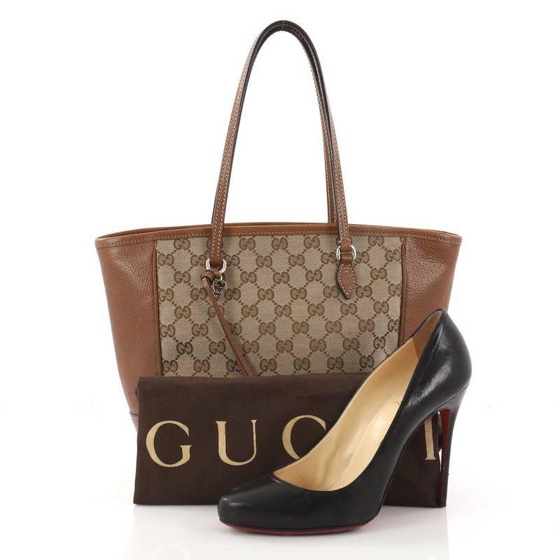 This authentic Gucci Bree Tote GG Canvas with Leather Small is perfect for everyday casual looks. Crafted from brown GG canvas with brown leather trims, this simple shopper-style tote features dual tall handles, small Gucci charm, and gold-tone