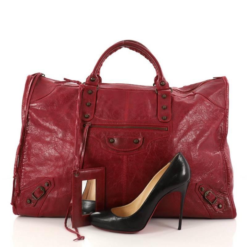 This authentic Balenciaga Weekender Classic Studs Handbag Leather is a stylish and fun accessory made for light travels and weekend getaways. Constructed from dark red leather, this oversized, lightweight carryall features braided woven handle