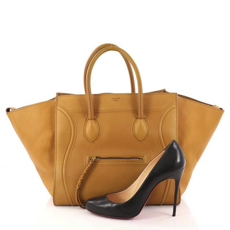 This authentic Celine Phantom Handbag Grainy Leather Medium is one of the most sought-after bags beloved by fashionistas. Crafted from mustard grainy leather, this minimalist tote features dual-rolled handles, an exterior front pocket, protective