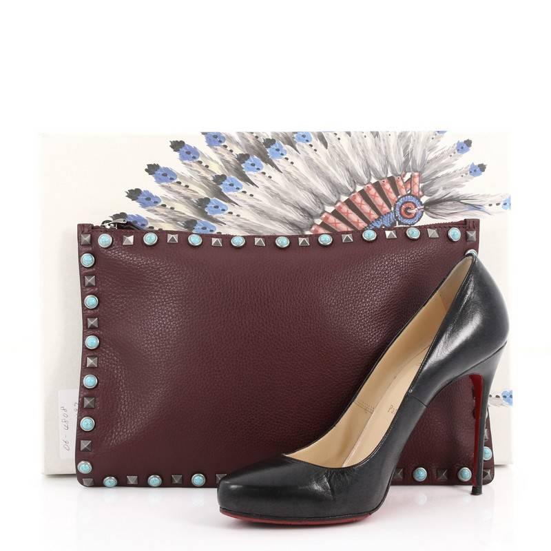 This authentic Valentino Rolling Rockstud Pouch Calfskin Large is a fun, exciting and bold accessory perfect for day or night out. Crafted from burgundy calfskin leather, this beautiful bag features a signature gunmetal rockstud and cabochon trims,