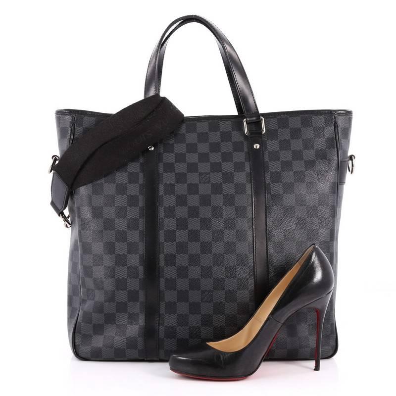 This authentic Louis Vuitton Tadao Handbag Damier Graphite MM balances style and functionality perfect for everyday excursions. Crafted from Louis Vuitton's signature damier graphite coated canvas with smooth black leather trims, this bag features