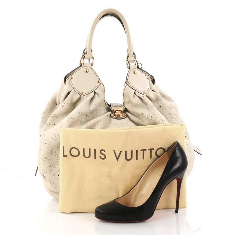 This authentic Louis Vuitton L-Hobo Mahina Leather is sleek and refined in design apt for the modern woman. Crafted in cream perforated monogram mahina leather, this feminine hobo features dual-rolled handles, buckle and stud details, side belt