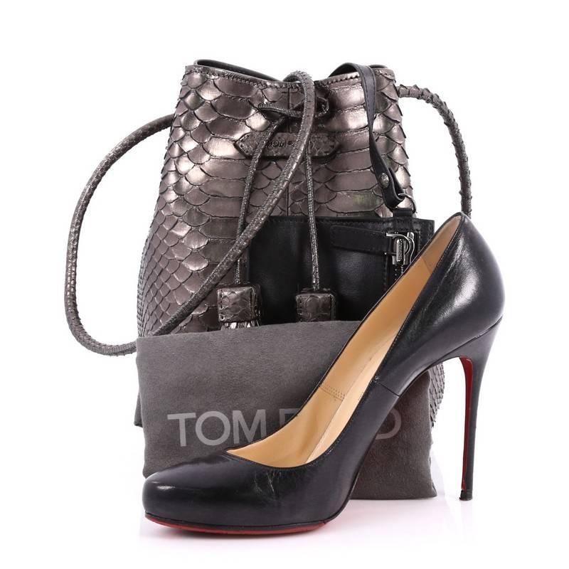 This authentic Tom Ford Tassel Bucket Bag Python Small is a chic bucket bag perfect for on-the-go moments. Crafted from genuine grey metallic python, this sleek understated bag features rolled crossbody strap, logo applique at center, tassel