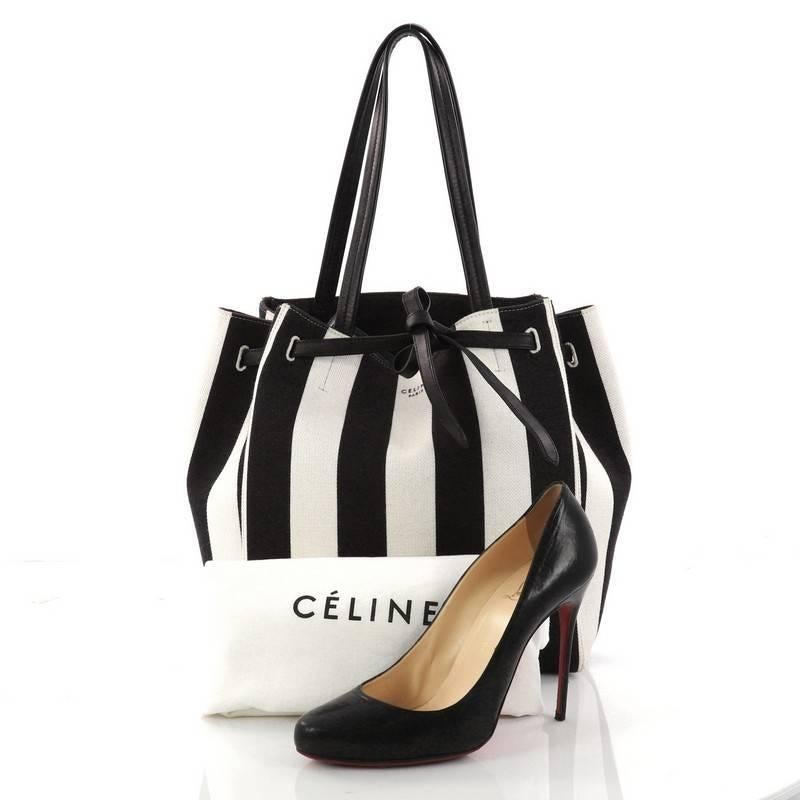 This authentic Celine Phantom Tie Cabas Tote Canvas Small is a fashionista's go-to stylish essential. Crafted from black and off-white striped canvas, this minimalist city tote features dual flat tall handles, stamped Celine logo, and silver-tone