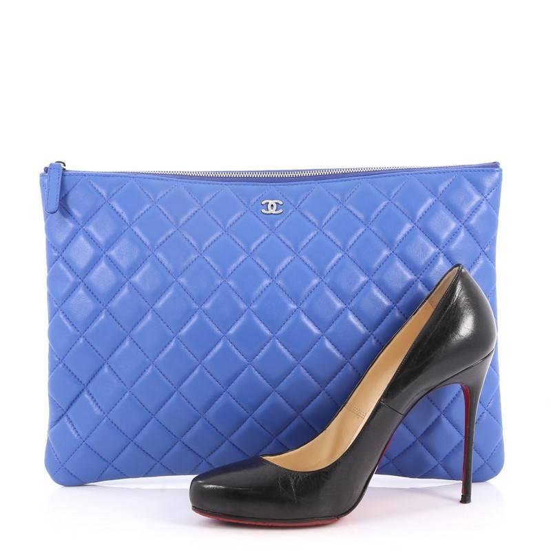 This authentic Chanel O Case Clutch Quilted Lambskin Large adds a touch of elegance to your everyday outfits. Crafted from blue quilted lambskin leather, this clutch features CC logo on the front, casino-motif lucky charms zip pull and silver-tone