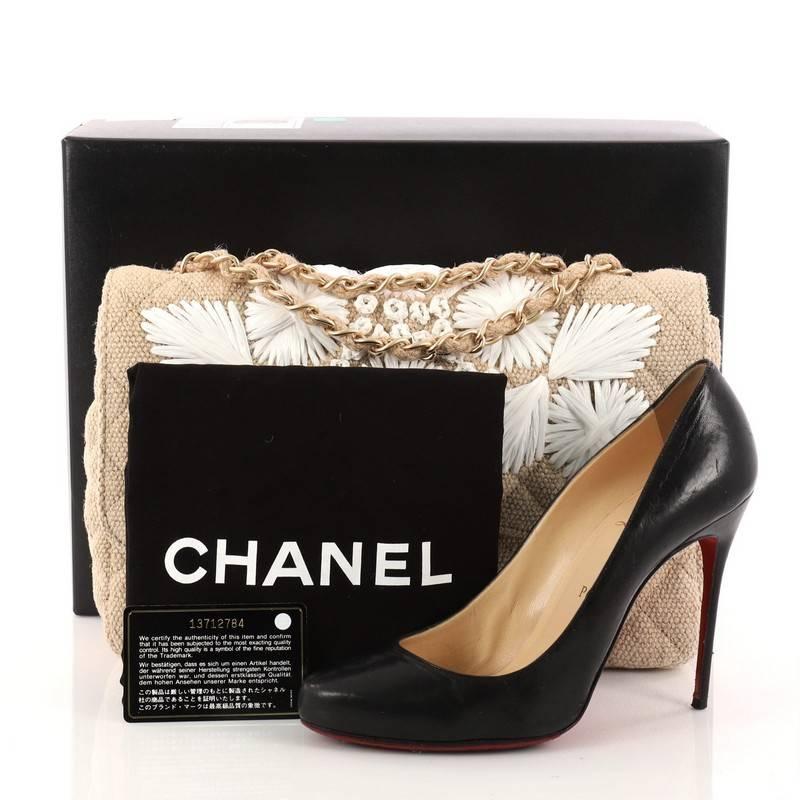 This authentic Chanel Country Coco Flap Bag Floral Embroidered Quilted Raffia Jumbo is a marvelous shoulder bag that is ideal for day looks. Crafted in beige quilted raffia, this stunning flap bag features woven-in raffia strap, embroidered floral