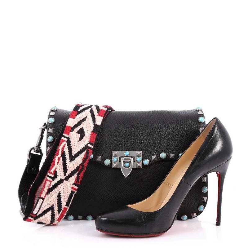 This authentic Valentino Rolling Rockstud Crossbody Bag Leather with Cabochons Medium is a fun, exciting and bold accessory perfect for nights out. Crafted from black soft leather, this beautiful flap bag features a Southwestern-inspired motif,