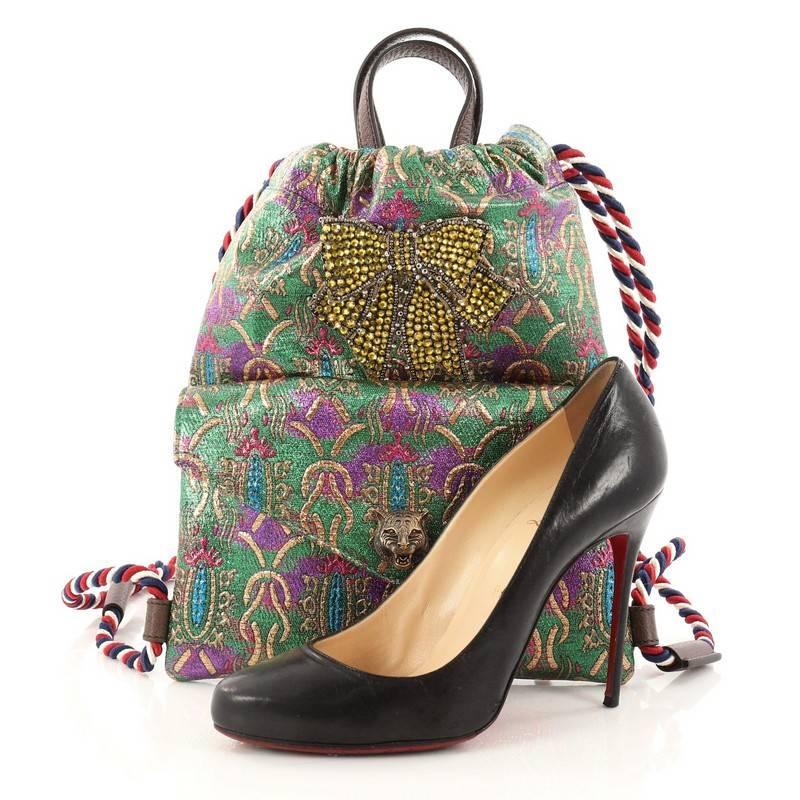 This authentic Gucci Animalier Drawstring Backpack Brocade Small displays and speaks to the dreamlike feel of the collection. Crafted in green multicolor brocade fabric, this chic backpack features, leather flat top handles, Sylvie web rope shoulder