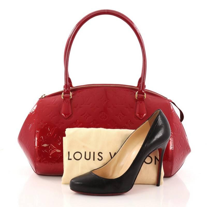 This authentic Louis Vuitton Sherwood Handbag Monogram Vernis GM is a uniquely shaped bag that showcases a modern take to Louis Vuitton's classic design. Crafted from red monogram vernis leather, this structured dome bag features dual-rolled leather
