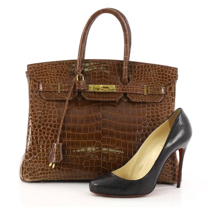 This authentic Hermes Birkin Handbag Miel Shiny Porosus Crocodile with Gold Hardware 35 is synonymous to traditional Hermes luxury. Crafted in genuine Miel Shiny Porosus crocodile, this eye-catching tote features dual-rolled top handles, a frontal